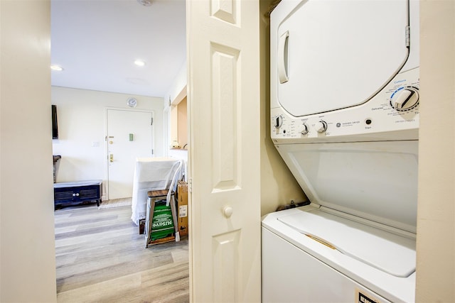 laundry area with light hardwood / wood-style flooring and stacked washing maching and dryer