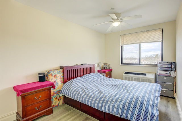 bedroom with light wood-type flooring, an AC wall unit, and ceiling fan