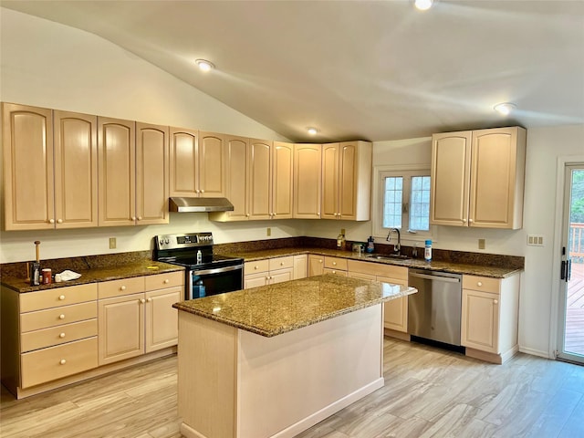 kitchen with lofted ceiling, dark stone counters, sink, a kitchen island, and stainless steel appliances