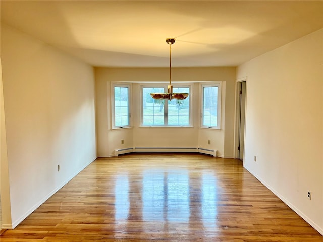 empty room with light hardwood / wood-style flooring, a notable chandelier, and a baseboard heating unit