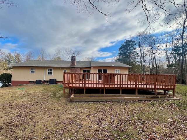 rear view of house featuring a lawn, a wooden deck, and central AC