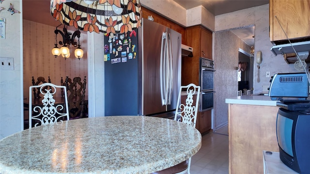 kitchen with brown cabinets, light countertops, an inviting chandelier, and tile patterned floors