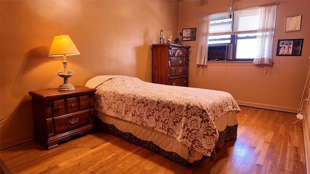 bedroom featuring baseboards, cooling unit, and hardwood / wood-style flooring