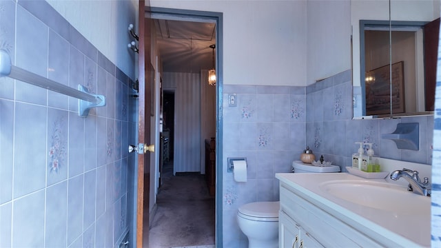 bathroom with toilet, vanity, and tile walls
