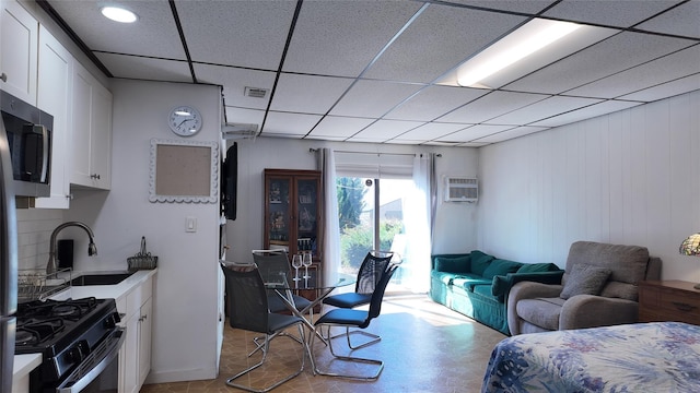 interior space featuring a sink, a wall unit AC, light floors, visible vents, and a drop ceiling