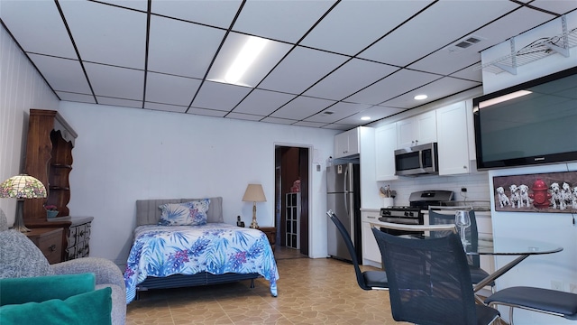 bedroom featuring freestanding refrigerator, visible vents, and a paneled ceiling