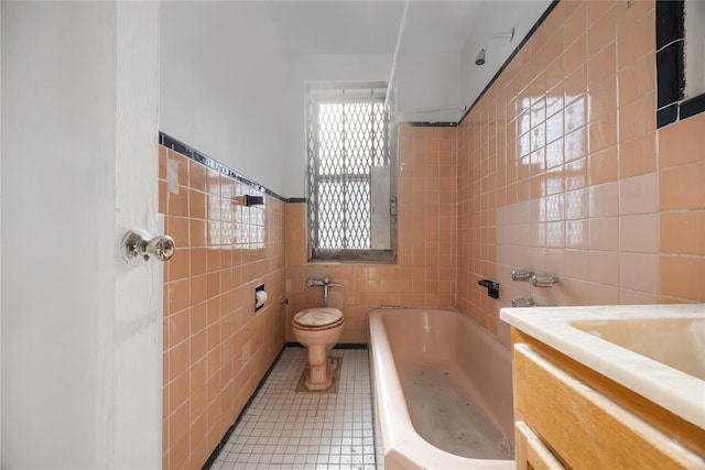 bathroom featuring vanity, tile patterned floors, toilet, tile walls, and a tub