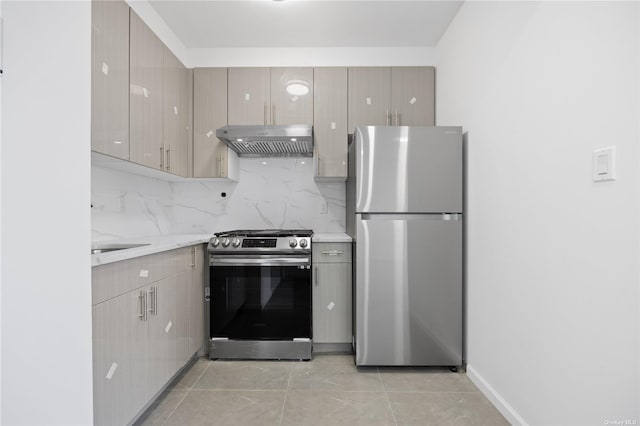 kitchen with light stone countertops, stainless steel appliances, tasteful backsplash, and light tile patterned flooring