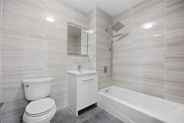 full bathroom with vanity, bathing tub / shower combination, tile patterned floors, toilet, and tile walls