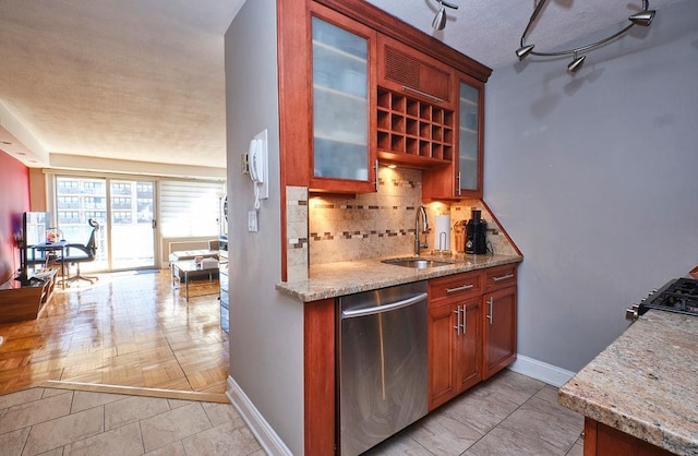 kitchen with light stone countertops, tasteful backsplash, sink, dishwasher, and light parquet flooring