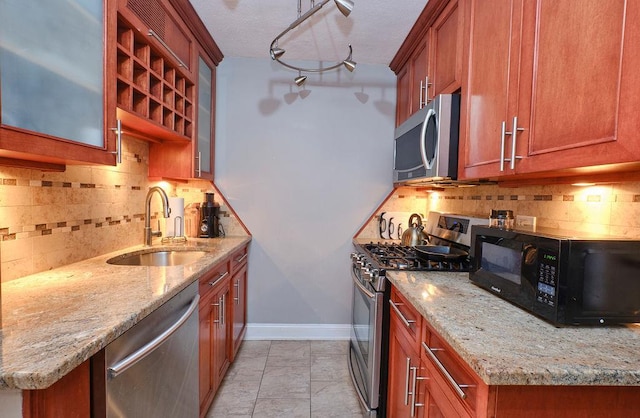 kitchen featuring sink, light stone countertops, light tile patterned floors, tasteful backsplash, and stainless steel appliances