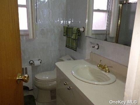 bathroom featuring vanity, toilet, and tile walls