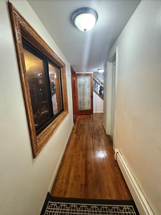 corridor featuring dark hardwood / wood-style flooring and a baseboard radiator