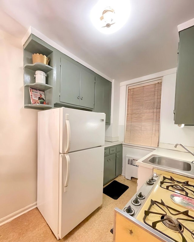 kitchen with radiator, sink, white fridge, and stovetop