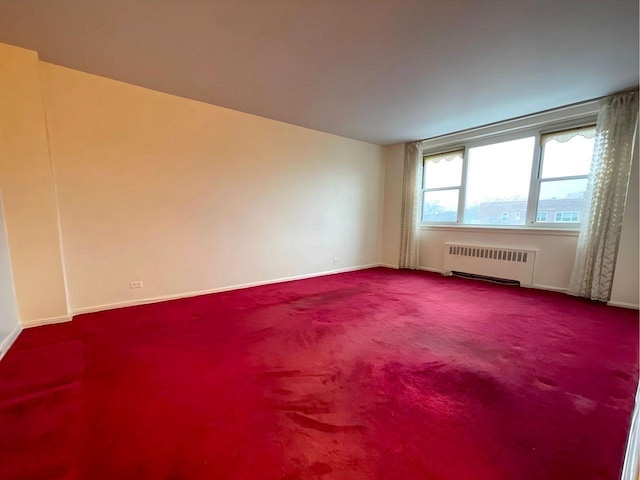 carpeted spare room featuring radiator