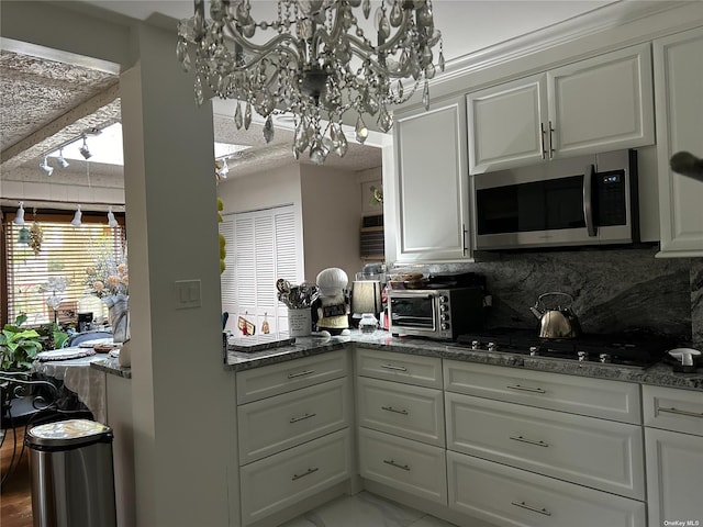 kitchen with white cabinets, backsplash, black gas stovetop, and dark stone counters