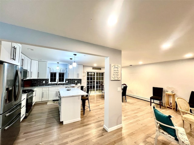 kitchen with white cabinetry, a kitchen bar, appliances with stainless steel finishes, decorative light fixtures, and a center island