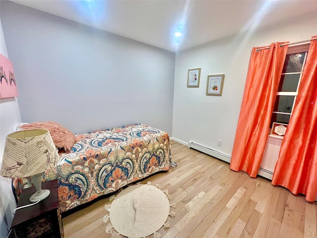 bedroom with wood-type flooring and a baseboard radiator