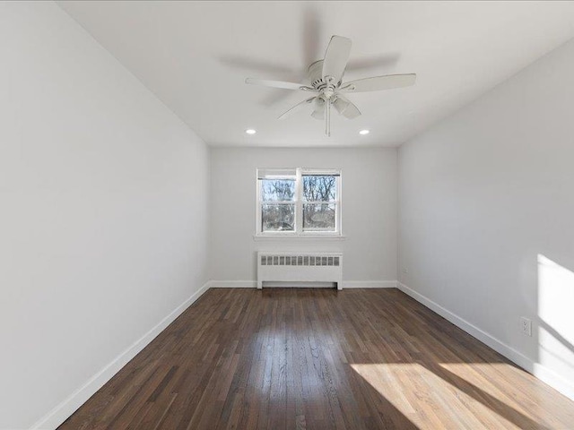 spare room featuring ceiling fan, dark wood-type flooring, and radiator