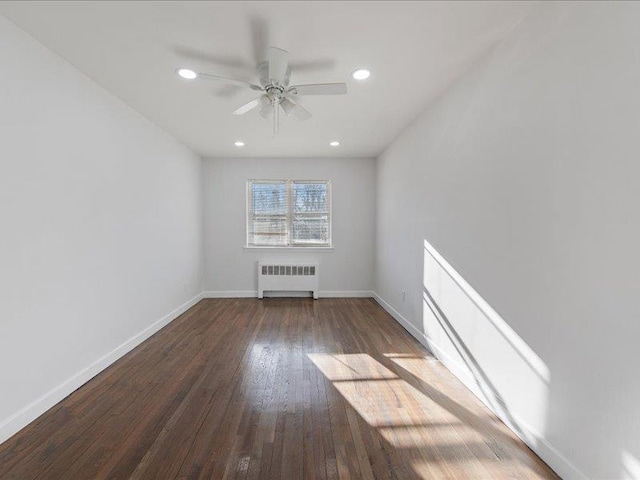 unfurnished room featuring dark hardwood / wood-style flooring, ceiling fan, and radiator heating unit