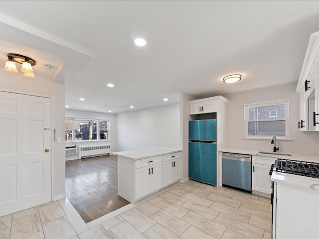 kitchen featuring radiator, sink, appliances with stainless steel finishes, white cabinetry, and kitchen peninsula