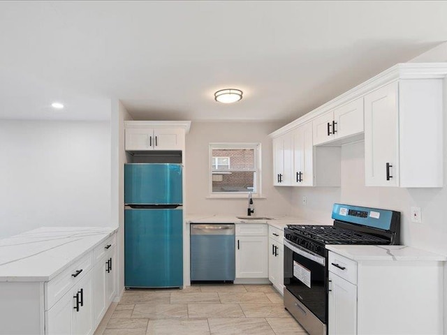 kitchen with white cabinets, appliances with stainless steel finishes, light stone counters, and sink