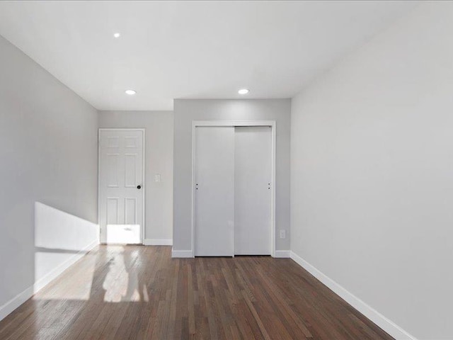 unfurnished bedroom featuring dark hardwood / wood-style flooring and a closet