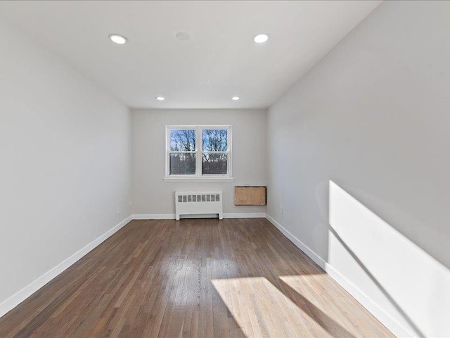 unfurnished living room featuring radiator and hardwood / wood-style floors