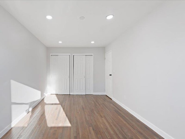 unfurnished bedroom featuring hardwood / wood-style floors and two closets