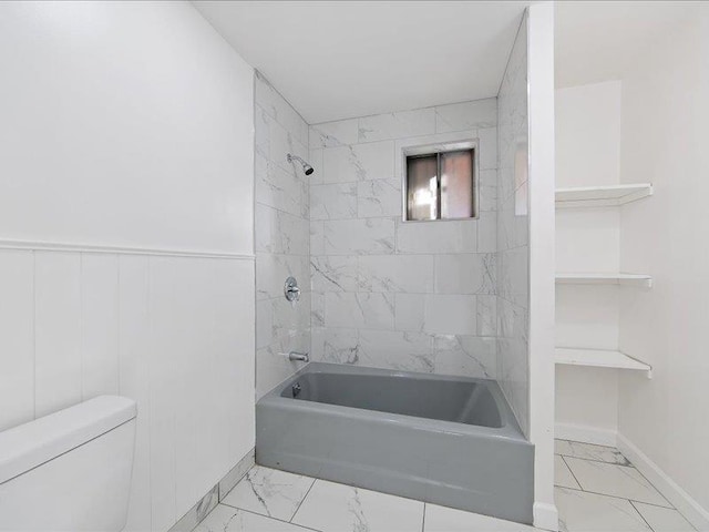 bathroom featuring tiled shower / bath combo and toilet