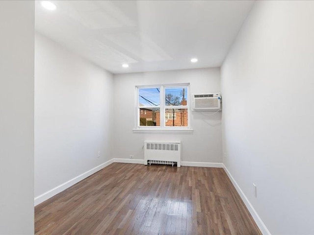 spare room with a wall mounted AC, hardwood / wood-style floors, and radiator