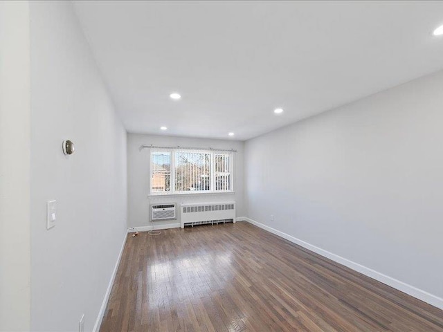 spare room with hardwood / wood-style floors, a wall unit AC, and radiator