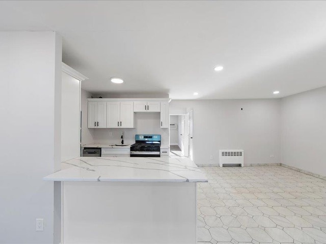 kitchen with radiator heating unit, stainless steel stove, light stone counters, kitchen peninsula, and white cabinets