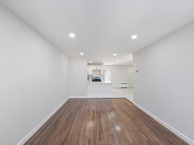 unfurnished living room with dark hardwood / wood-style flooring and radiator heating unit