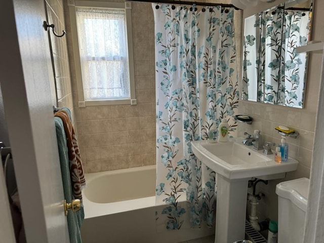 bathroom featuring tile walls, tiled shower / bath combo, a wealth of natural light, and toilet