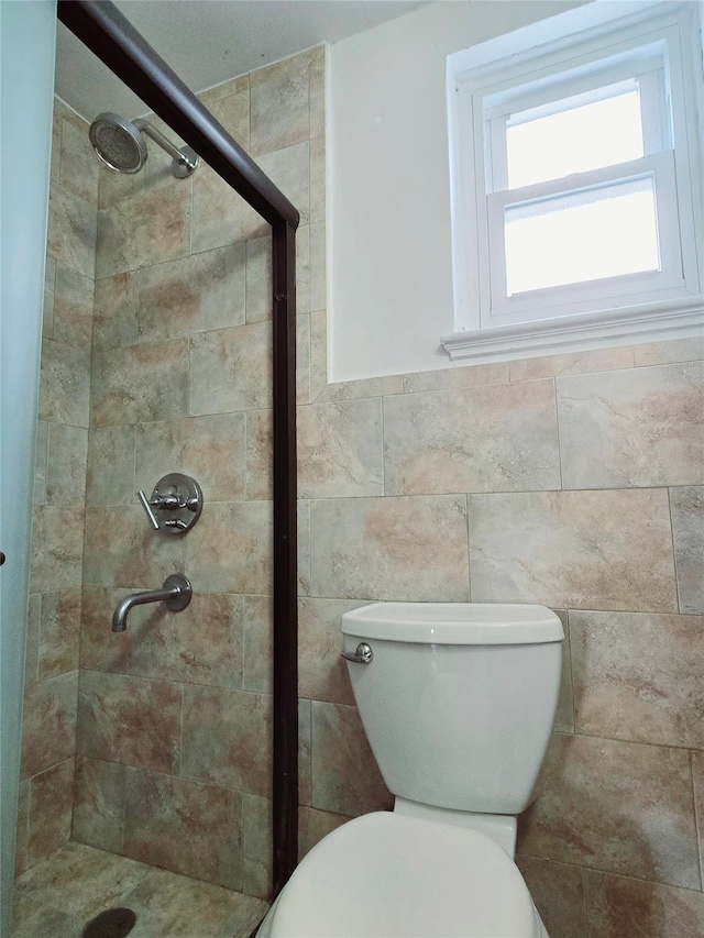 bathroom with a tile shower and toilet