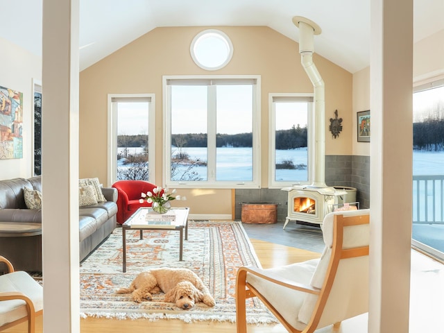 sunroom featuring vaulted ceiling, plenty of natural light, and a wood stove