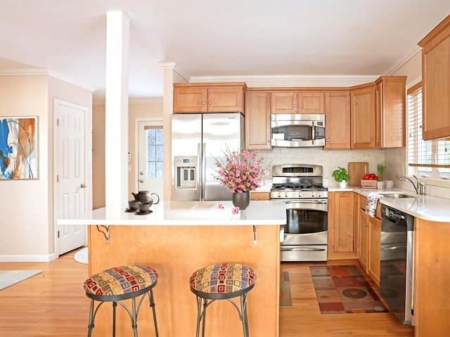 kitchen with stainless steel appliances, a breakfast bar, backsplash, and light wood-style flooring