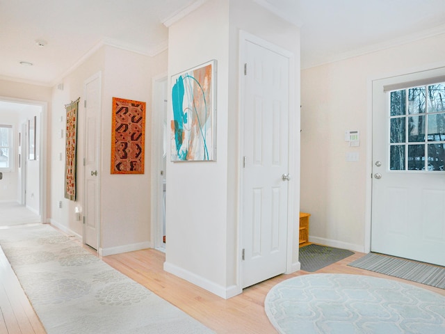 entryway featuring light wood finished floors, ornamental molding, and plenty of natural light