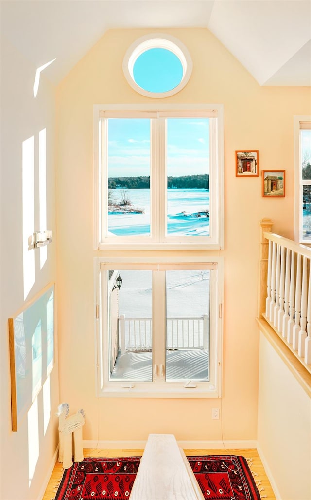 doorway to outside with lofted ceiling, baseboards, and wood finished floors