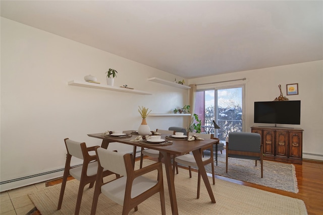 dining area with wood-type flooring and a baseboard heating unit