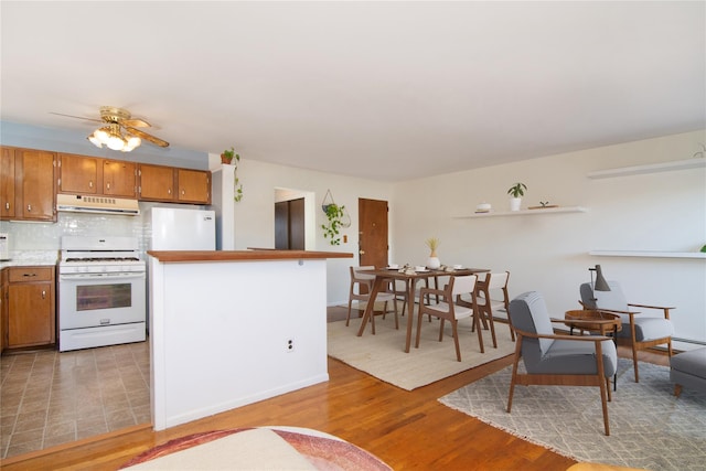 kitchen with ceiling fan, white appliances, light hardwood / wood-style floors, and decorative backsplash