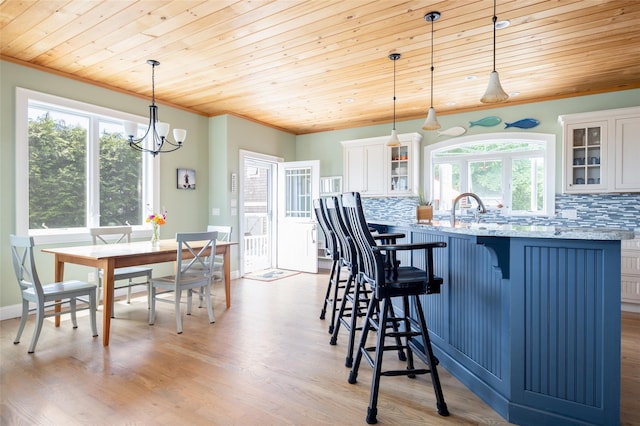 kitchen featuring wooden ceiling, white cabinets, hanging light fixtures, light stone countertops, and tasteful backsplash