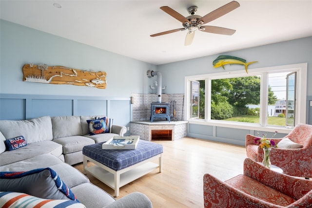 living room featuring a wood stove, ceiling fan, and light hardwood / wood-style flooring