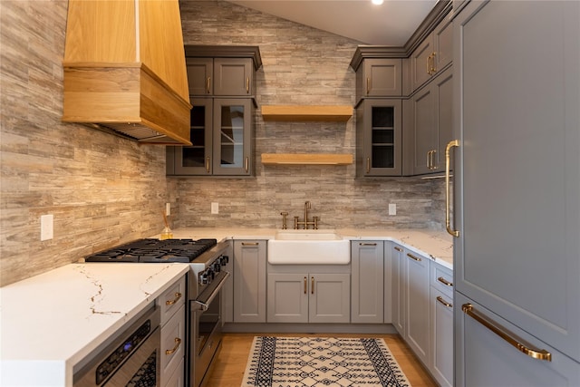 kitchen with gray cabinets, light stone countertops, sink, and high end appliances