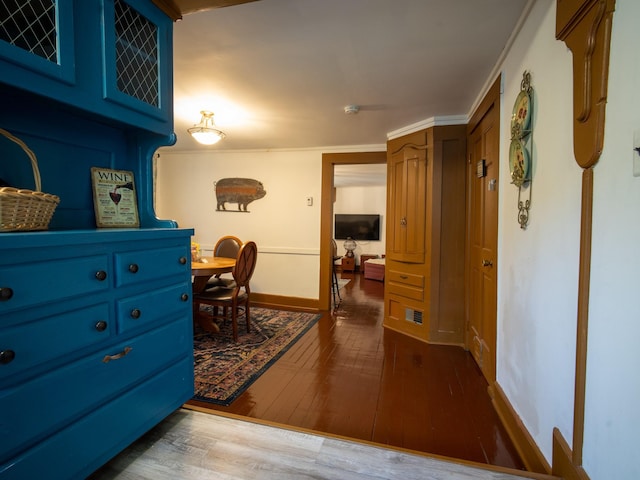 corridor with dark hardwood / wood-style floors and crown molding