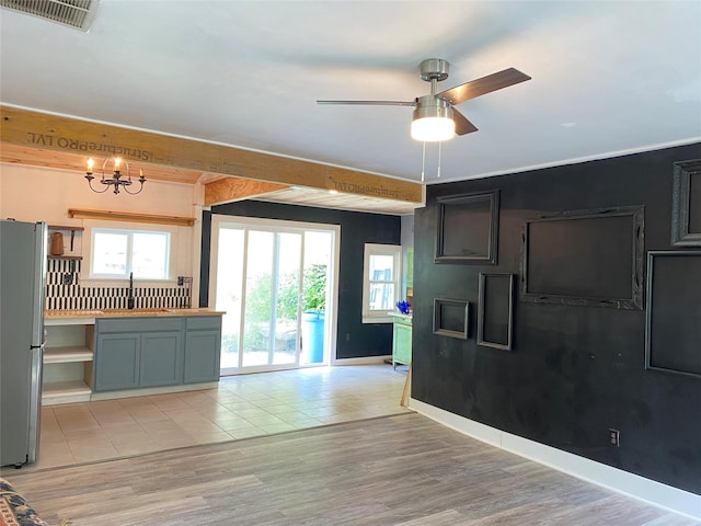 kitchen featuring backsplash, ceiling fan with notable chandelier, sink, light hardwood / wood-style flooring, and stainless steel fridge