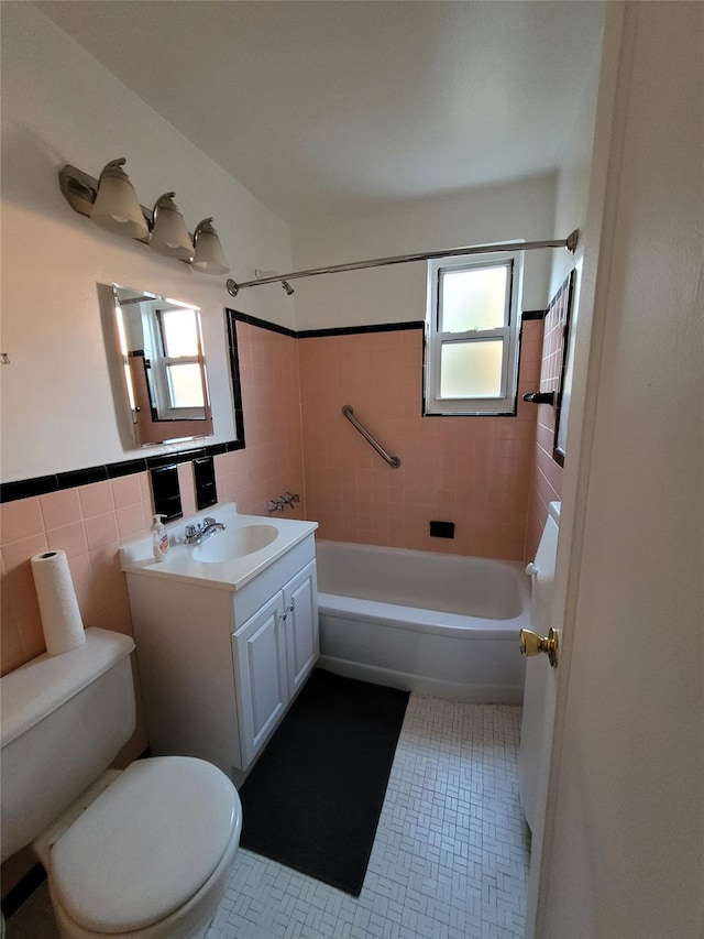 full bathroom with vanity, toilet, tile walls, and a healthy amount of sunlight