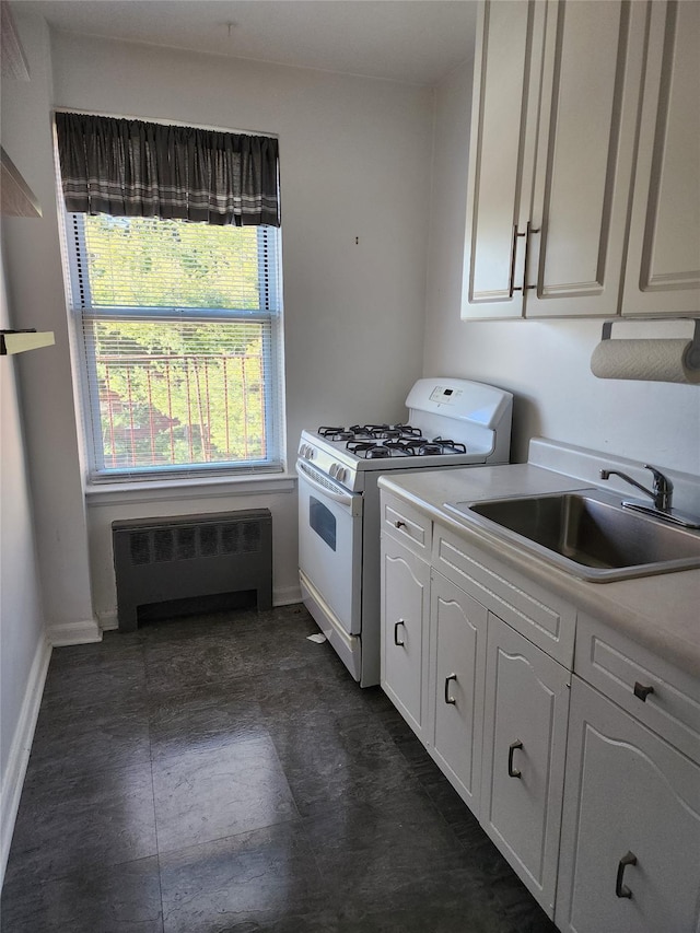 kitchen with white cabinets, white gas range, sink, and radiator