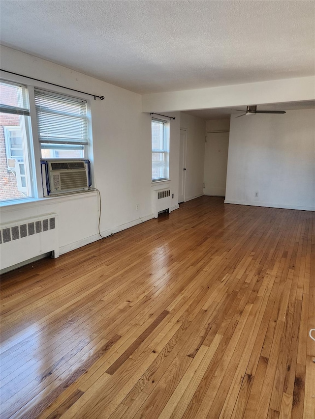 unfurnished room featuring ceiling fan, a textured ceiling, radiator, and light hardwood / wood-style flooring